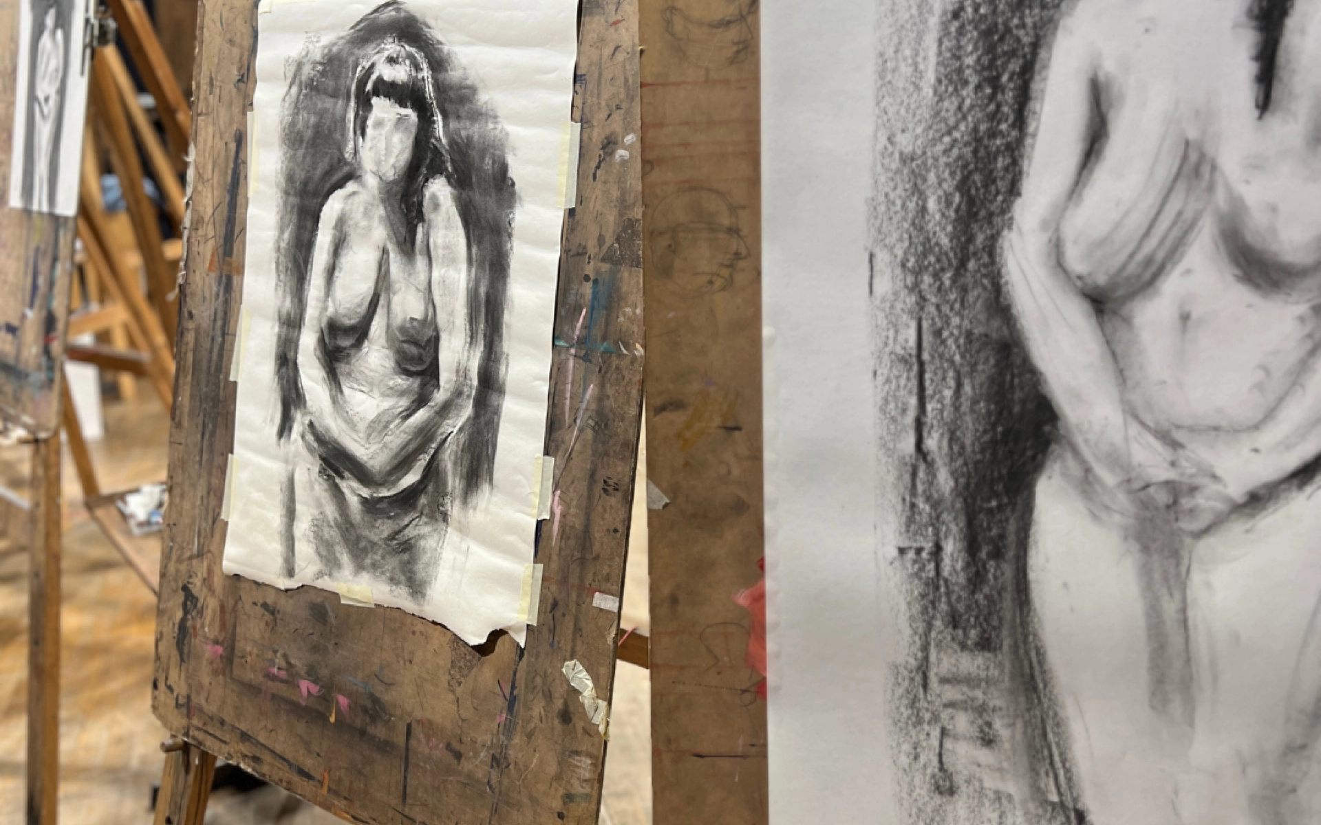 Images of two easels, with charcoal drawn pieces depicting a nude woman with black hair, no facial features and her hands held in front of her.