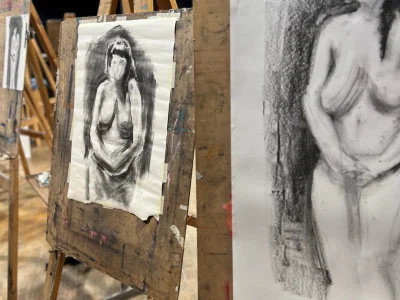 Images of two easels, with charcoal drawn pieces depicting a nude woman with black hair, no facial features and her hands held in front of her.