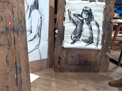 Three easel's upright showing a sketched image of a nude woman.