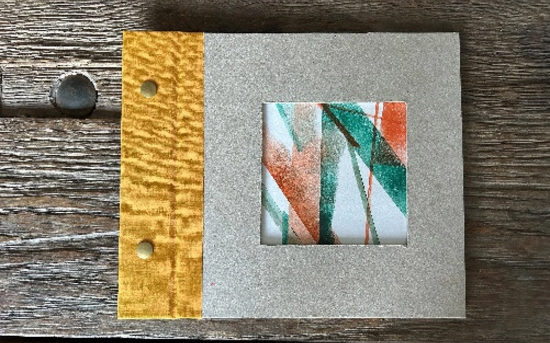 An imagine featuring a handmade sketchbook using scraps, unfinished prints and spare bits. It is squared, hand-bound and textured with a yellow spine.