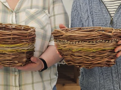 An image of two people holding their own woven wooden baskets in their hands.