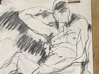 Charcoal drawing of a reclining nude figure on a surface, one arm behind the head; bold lines with heavy shading across the torso.