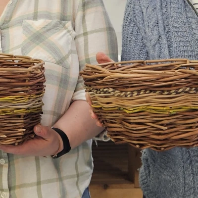 An image of two people holding their own woven wooden baskets in their hands.