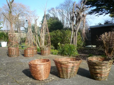An image of three woven willow baskets in a garden space, giving an example of how your baskets will look upon completing the workshop.